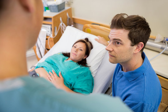 Man And Pregnant Woman Listening To Nurse In Hospital