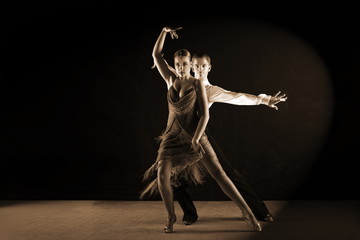 Obraz premium Latino dancers in ballroom against black background