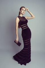 Elegant blonde in luxury black dress holding a handbag