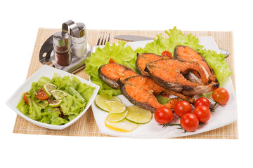Baked trout with vegetables on a white background
