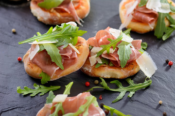 Minipizzen mit Parmaschinken und Rucola auf Schieferplatte