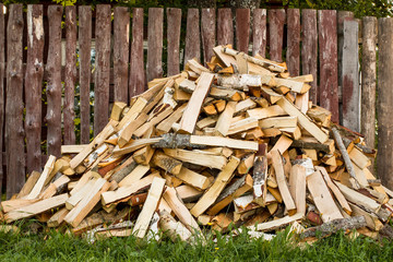 pile of chopped firewood lies near the fence at the house