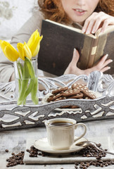 Cup of coffee. Woman reading a book in the background