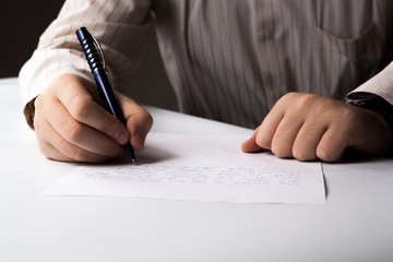 man is  writting on a sheet of paper