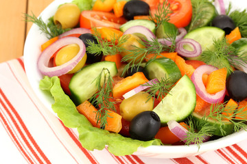 Fresh salad in plate on wooden table