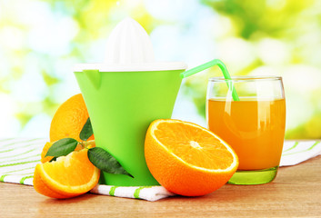 Citrus press, glass of juice and ripe oranges