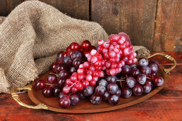 Golden tray with grape on wooden background