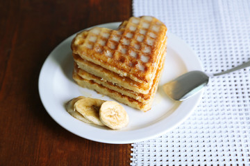 Sweet Belgium waffles with banana, on wooden table background