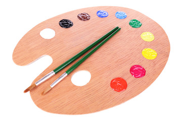 Wooden art palette with paint and brushes isolated on white