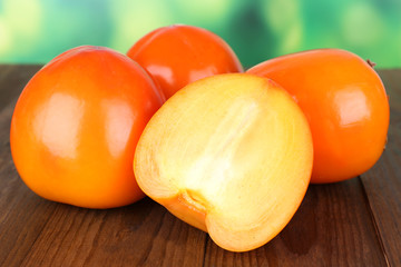 Ripe persimmons on table on bright background