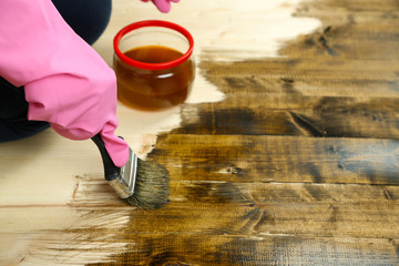 Applying protective varnish to wooden fence,