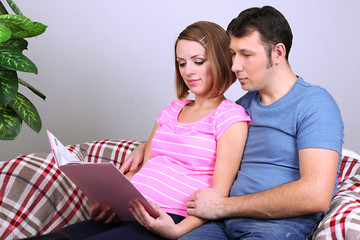 Young pregnant woman holding book and her husband