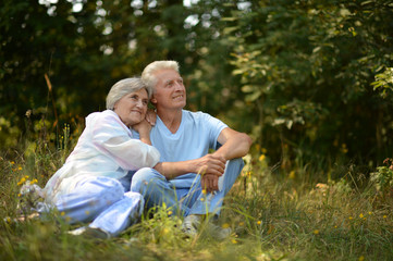 Happy elder couple resting on grass