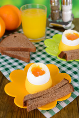 Boiled eggs in egg cups on table on bright background
