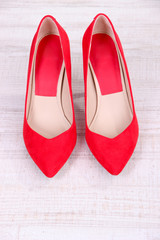 Beautiful red female shoes, on wooden background