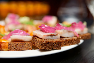 Herring canapes in plate, close-up