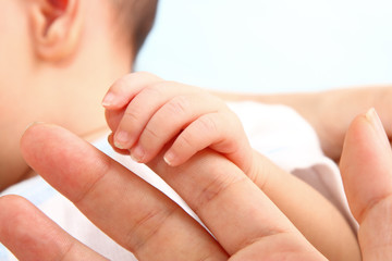 A baby holding his mother's finger