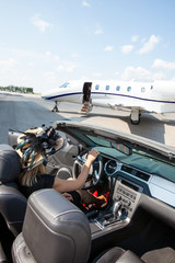 Woman In Convertible With Private Jet At Terminal
