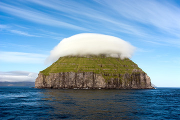 Uninhabited small island covered by a cap of clouds - 60267294