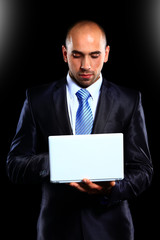 Business man with a laptop -over a black background