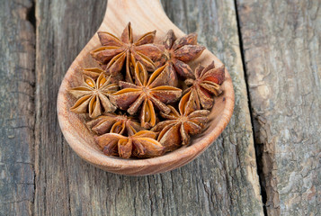 star anise in a spoon on wooden surface