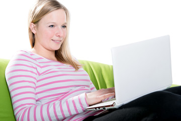 Junge Frau sitzt entspannt mit Notebook auf dem Sofa