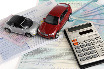 Два автомобиля, калькулятор на фоне полиса, извещения и денег