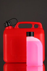 Plastic canister with oil and liquid for car on grey background