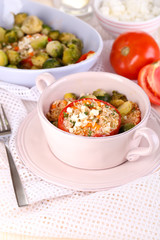Stuffed tomatoes in pan and bowl on wooden table close-up