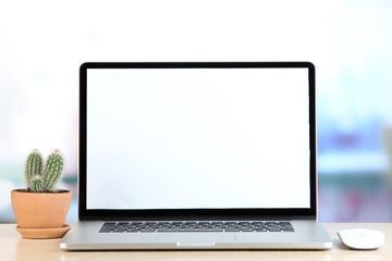 Laptop and cactus in flowerpot on wooden table