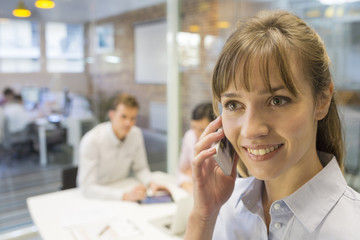 Portrait of smiling businesswoman on mobile phone in meeting