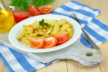 Ruddy fried potatoes on plate on wooden table close-up