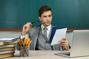 Young teacher sitting in school classroom