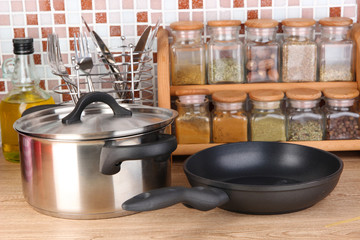 Pot and pan in kitchen on table on mosaic tiles background