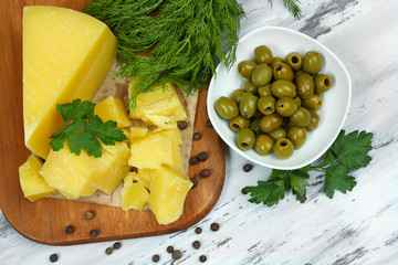 Parmesan cheese, fresh herbs and olives on wooden background