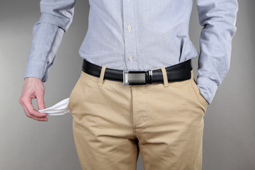 Man showing his empty pocket on grey background