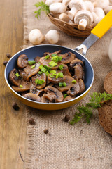 Delicious fried mushrooms in pan on table close-up