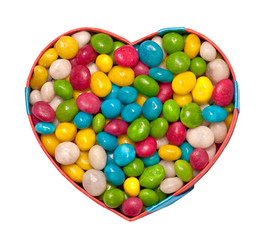 Heart-shaped box filled with colorful candies isolated on white 