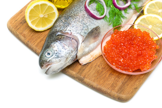 trout, red caviar, lemon and vegetables on a cutting board close