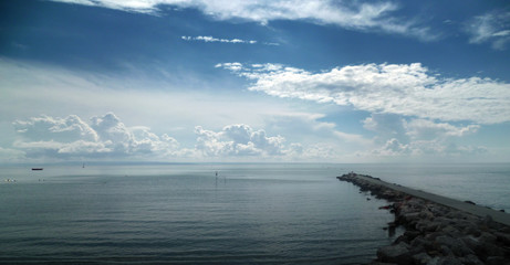 panoramic photo of sea coast with a stone jetty