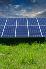 solar photovoltaic cell panels on green grass under cloudy sky