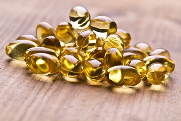 Cod liver oil omega 3 gel capsules isolated on wooden background