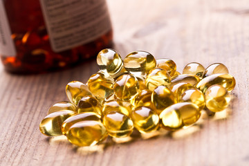 Cod liver oil omega 3 gel capsules isolated on wooden background