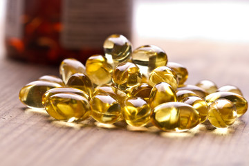 Cod liver oil omega 3 gel capsules isolated on wooden background