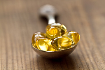 Cod liver oil omega 3 gel capsules isolated on wooden background