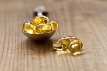 Cod liver oil omega 3 gel capsules isolated on wooden background