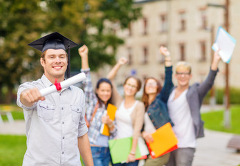smiling teenage boy in corner-cap with diploma
