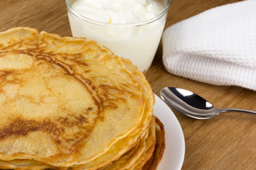 pancakes on a plate with a cup of sour cream