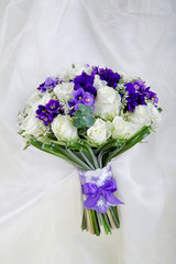 Wedding bouquet of the bride against a white fabric