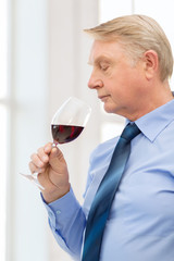 older man smelling red wine